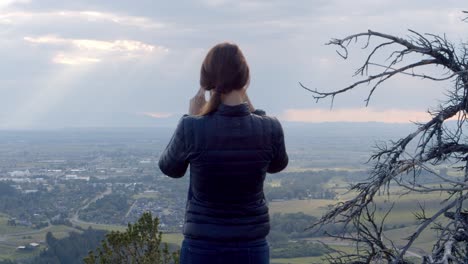Woman-looking-over-the-green-valley-below-on-a-summer-day