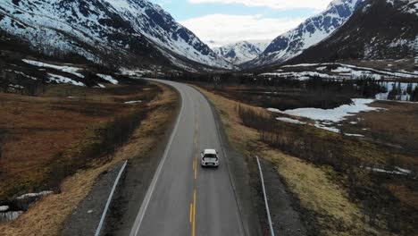 Slow-motion-drone-shot-following-a-car-driving-through-a-beautiful-valley