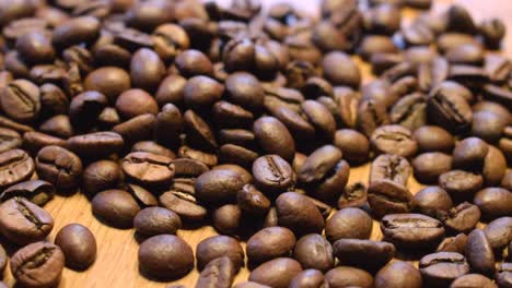 Geröstete-Kaffeebohnen,-Die-Zum-Streuen-Auf-Einen-Holztisch-Fallen
