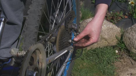 The-Man-Inserts-the-Bicycle-Wheel-into-the-Old-Bicycle-and-Puts-On-the-Chain