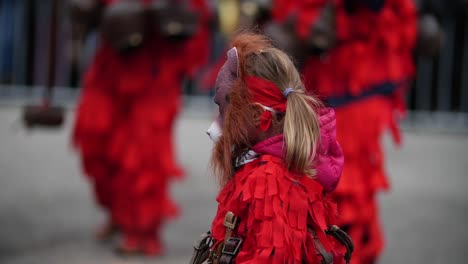 Bulgarisches-Kuker-Kostüm-Eines-Kindes,-Das-Einen-Holzhammer-Hält-Und-In-Rot-Mit-Einer-Bärenmaske-Gekleidet-Ist