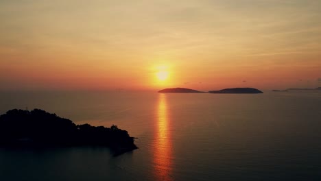 Aerial-view-of-a-beautiful-sunrise-behind-the-mountains-island-over-the-ocean-and-flying-smooth-over-the-sea-in-the-morning-viewpoint-nature-landscape-of-Thailand