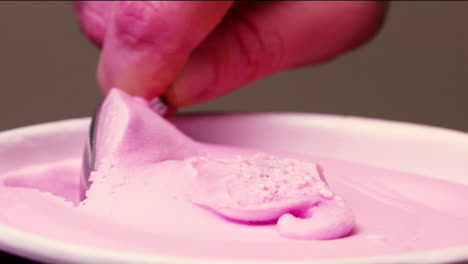 Close-up-scooping-pink,-cherry-ice-cream-from-a-container
