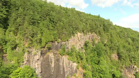 Vertical-cliffs-covered-in-pine-forests-in-Canada-on-blue-sky-with-few-clouds