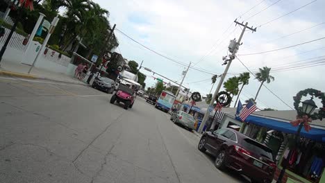 Dutch-Angle-Shot-of-Key-West-Street-With-Streep-Lamps-Decorated-With-Christmas-Wreaths-With-Golf-Cart-Driving-Toward-Camera