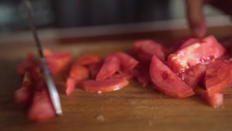 cutting-tomato-slices-on-wooden-cutting-board,-female-hand,-close-up