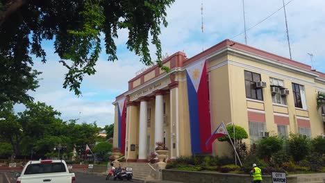 Hauptgebäude-Des-Bürgermeisteramtes-Der-Stadt-In-Davao-City,-Philippinen-Mit-Philippinischer-Flagge-Und-Person,-Die-Die-Straße-Fegt