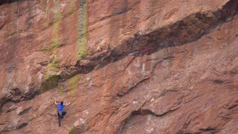 Woman-climbing-a-steep-rock-using-climbing-gear