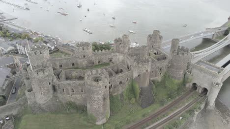 Medieval-landmark-historic-Conwy-town-castle-aerial-view-above-Welsh-seaside-landscape-wide-orbit-right