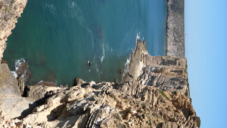Vertical-Video-of-Steep-Cliffs-and-Ocean-Waves-on-Sagres-Coastline,-Portugal