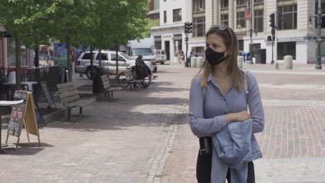 Girl-walks-alone-on-sidewalk-with-black-protection-mask-during-corona-pandemic