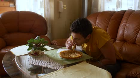 Young-male-eating-a-pancake-in-a-living-room