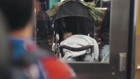 A-Cute-Japanese-Baby-In-A-Stroller-Riding-A-Train-In-Tokyo,-Japan---close-up-slowmo