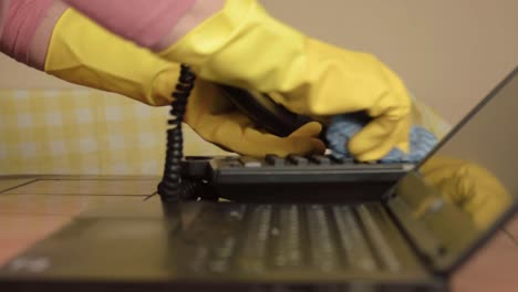 Hands-in-rubber-gloves-cleaning-office-phone-with-cloth