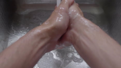 Closeup-Of-A-Person's-Hand-Washing-With-Soap-Under-Clean-Tap-Water-From-A-Faucet---High-Angle-Shot