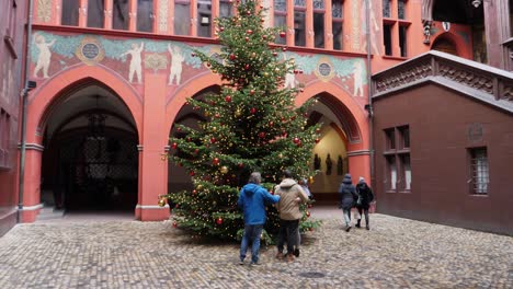 Full-shot,-Family-get-together-in-front-of-a-Christmas-tree,-Town-hall-interior-of-Basel-in-the-background