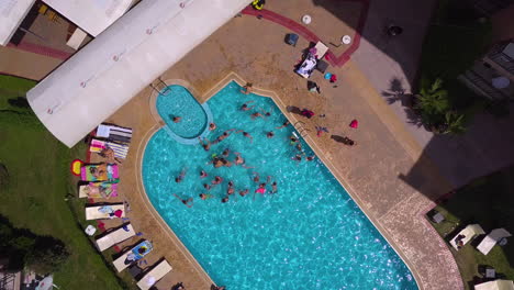 Draufsicht-Drohnenaufnahme-Des-Swimmingpools-Im-Hotelkomplex-Mit-Spielenden-Kindern