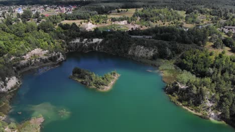Luftaufnahme-Des-Wunderschönen-Sees-Mit-Kleiner-Insel-Und-Blauem-Wasser,-Umgeben-Von-Felsigen-Klippen