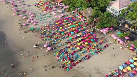 Famous-double-six-beach-crowded-by-tourists-with-umbrella-at-sunset,-aerial,-Bali