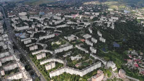 Aerial-View-of-Geometrically-Shaped-Buildings-in-a-City-Surrounded-by-Trees-Near-Busy-Road