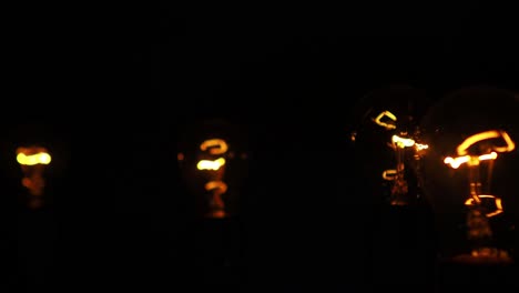 Incandescent-lamps-with-a-red-orange-colored-tungsten-filament-on-a-black-background,-slow-pan-shot