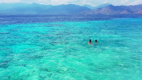 Two-young-female-teenagers-swimming-in-the-crystal-clear-aqua-water-in-perfect-tourist-holiday-destination-Indonesia