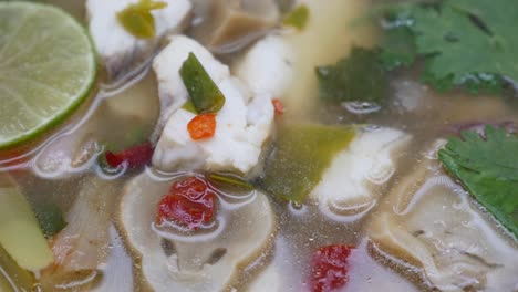 Nahaufnahmen-Einer-Klaren-Tom-Yum-Suppe-Mit-Wolfsbarsch-Und-Pilzen,-Dem-Berühmten-Thailändischen-Gericht,-Das-Für-Seinen-Aromatischen-Und-Würzigen-Geschmack-Bekannt-Ist