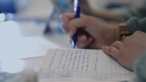 Soft-orbit-dolly-close-up-shot-of-woman-writing-in-notebook-in-swedish