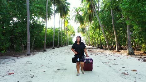 Excited-Asian-woman-arriving-on-the-paradise-island-with-the-wheeled-suitcase-in-the-casual-clothing