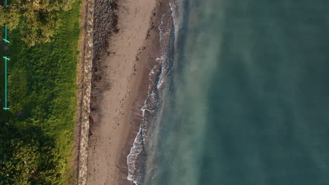 Birds-eye-aerial-footage-over-a-New-Zealand-shore-with-blue-ocean-waters