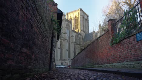 Dolly-in-of-large-cathedral-from-low-angle-on-cobbled-alley-way-in-historic-city-of-York