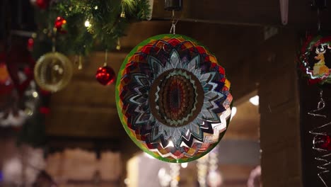 Farbiges-Windspinnen-Mandala,-Das-Sich-Im-Wind-Dreht,-Während-Es-Auf-Dem-Weihnachtsmarkt-Hängt