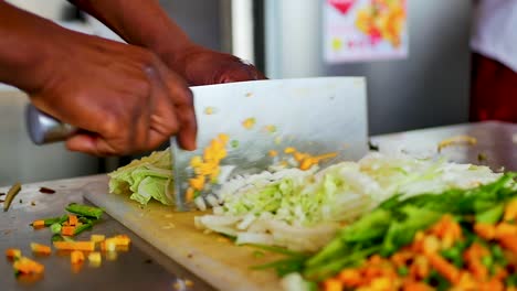 A-chef-chopping-vegetable-with-a-cleaver-knife-on-a-white-cutting-board-slow-motion,-static-shot