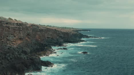 4k-Aerial-high-volcanic-cliff-on-calm-ocean-Drone-dolly-in-shot