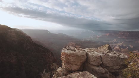 Grand-Canyon-cliff-edge-looking-out-over-sunset,-reveals-the-valley-below---Gimbal---Arizona-USA