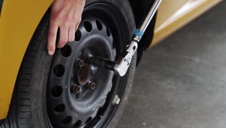 Mechanic-tightens-wheel-nuts-on-race-car-with-wrench