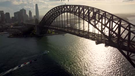 Toma-Aérea-De-Drones-Del-Icónico-Puente-Del-Puerto-De-Sydney-Con-Automóviles-Que-Viajan-Al-Paisaje-Urbano-Emblemático-Del-Turismo-Al-Final-De-La-Tarde-Nsw-Australia-4k