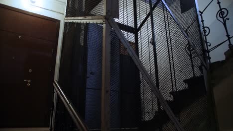 Old-wooden-elevator-ascends-in-metal-shaft-in-building-with-staircase