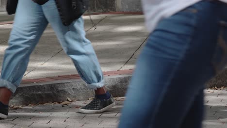 Close-up-slow-motion-shot-of-people’s-legs-and-feet-as-they-walk-up-and-down-a-busy-sidewalk-in-the-city-center-during-a-lunch-break-on-a-normal-business-day