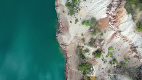 Top-down-fly-over-view-of-a-mine-construction-site-with-blue-lake