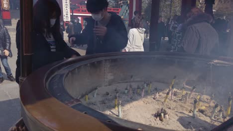 Sensoji-temple,-tourists-visiting-famous-Tokyo-site-taking-in-incense