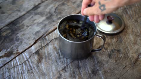 Hand-stiring-healthy-guayusa-tea-leaves-in-hot-water-on-wooden-table