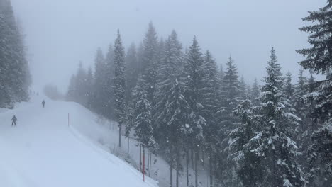 Gente-Esquiando-En-La-Montaña-Nevada-Con-Nieve-Cayendo-Sobre-Los-Pinos-Durante-La-Temporada-De-Invierno-En-Austria---Ascenso-De-Alto-ángulo