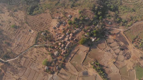 Falling-drone-shot-of-a-rural-Indian-village-surrounded-by-farmlands