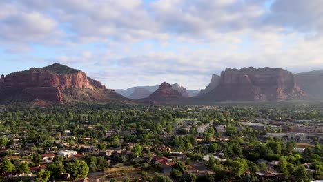 Descending-aerial-over-neighborhood-of-houses,-Bells-Rock-and-Courthouse-Butts,-cloudy-Sedona-Arizona