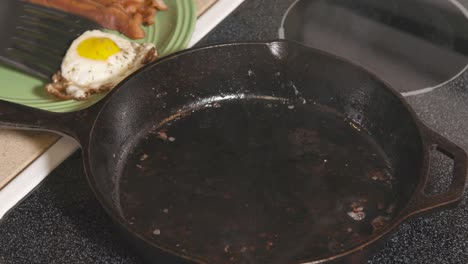 Cast-Iron-pan-on-stove-frying-egg-and-removing-from-pan