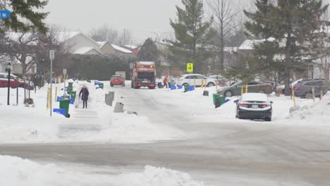 Garbage-truck-and-man-collecting-garbage-down-a-snowy-street