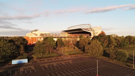 Iconic-Anfield-Liverpool-football-club-empty-car-park-rising-reveal-of-stadium-at-sunrise-aerial-view