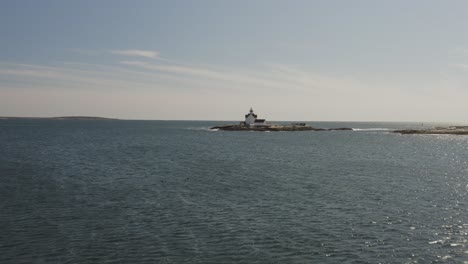 Wellen,-Die-Eine-Kleine-Felsige-Insel-Mit-Einem-Weißen-Leuchtturm-Umspülen,-Küste-Von-Maine,-Antenne