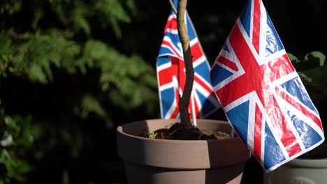 Eine-Reihe-Britischer-Union-Jack-Flaggen,-Die-In-Einem-Englischen-Garten-Im-Wind-Wehen